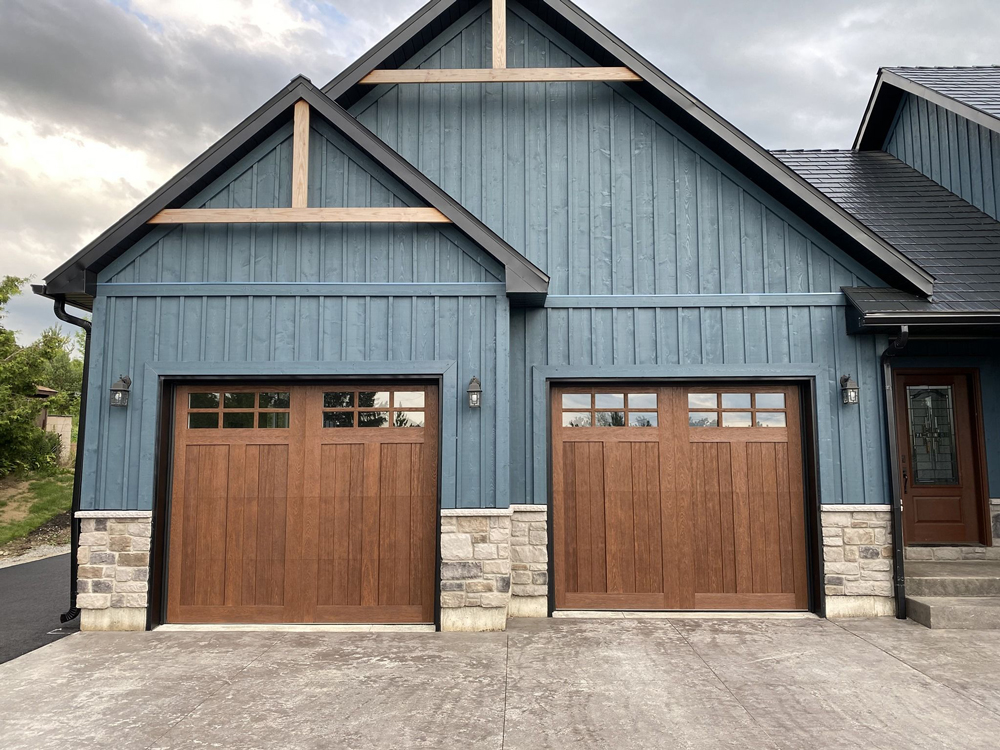 A blue home with two large wooden garage doors.