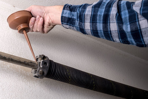 A close-up of a man's hand reaching up to a garage spring.