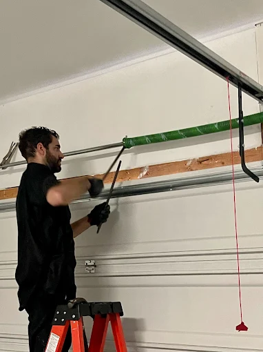 what causes garage door springs to break near Austin, TX - Eco Garage Door Services technician repairing garage door springs
